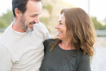 Fototapeta premium Romantic couple smiling and cuddling looking at each other on a sunny day