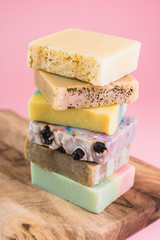 colorful handmade soaps on wooden board against pink background