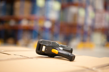 Close up view of bar code scanner placed on cardboard boxes in large distribution warehouse facility. Logistics and distribution concept.