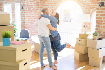 Young couple hugging in love arround carboard boxes at new home, celebrating very happy moving to new apartment