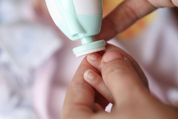 Cut nails with nail file, Mother filling baby nails using Automatic baby nail file machine.