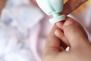Cut nails with nail file, Mother filling baby nails using Automatic baby nail file machine.