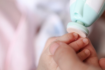 Cut nails with nail file, Mother filling baby nails using Automatic baby nail file machine.