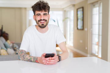 Young hipster man smiling using smartphone at home