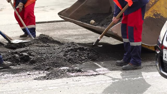 Workers remove shovels old cut asphalt from the road for laying new asphalt. Preparation of the road for laying new asphalt.