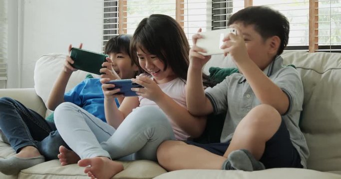 Group of children friend using smartphone to play game together at home. Children playing game with happy emotion.
