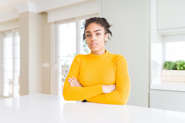 Beautiful african american woman with afro hair wearing a casual yellow sweater skeptic and...