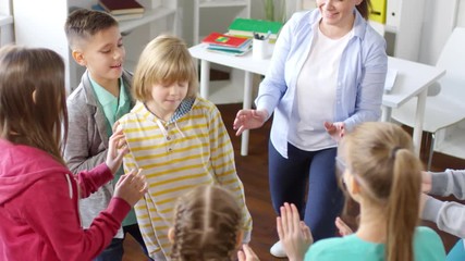Top shot of smiling blond teenage boy with closed eyes standing in middle of circle and playing psychological game with friends and mental health coach, falling slowly and others catching him
