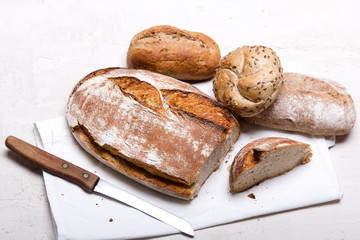 Tasty dark bread and buns  on white background, copy space. Bakery products, wholemeal bread and brown whole wheat buns