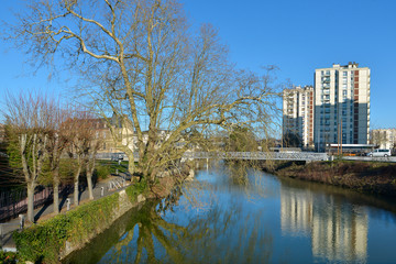 Fototapeta na wymiar Trees and apartment blocks on the bank of river Sarthe at Alençon of the Lower Normandy region in France