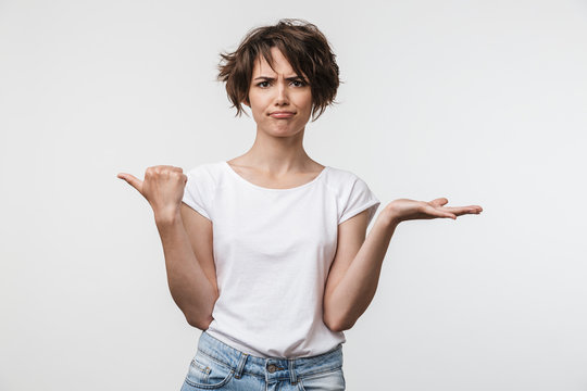 Image of perplexed woman with short hair in basic t-shirt pointing finger aside at copyspace