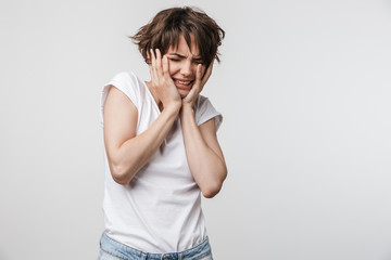 Photo of stressed woman with short brown hair in basic t-shirt grabbing her head and crying