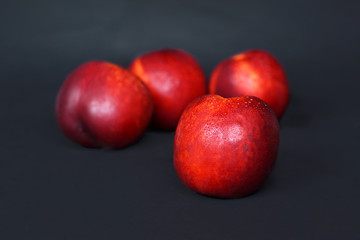 Fototapeta na wymiar Fresh ripe Nectarine in front of blurry fruits on black background