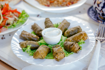 Dolma - rolls made from grape leaves and meat, on white plate.