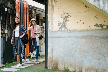 Walk way on garden is make from stone in small town. two asian women tourists passing through lane on slate pathway curiously looking around. happy girl friends sightseeing in lovely attraction