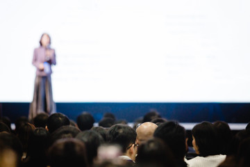 Blurry of woman speaker speech on stage in auditorium for shareholders' meeting