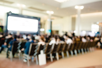 Blurry of auditorium for shareholders' meeting or seminar event with projector and white screen