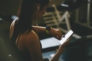 Beautiful young woman using smart watch at the gym