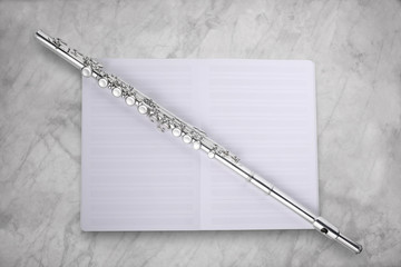 transverse flute and empty music score rest on a marble table with clipping path on the subject and...