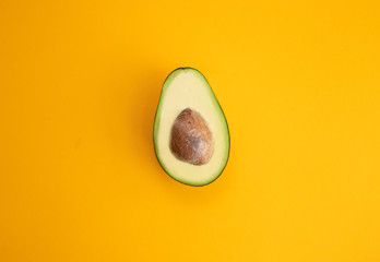 Close up ripe sliced avocado on bright yellow background top view flat lay. Tropical summer...