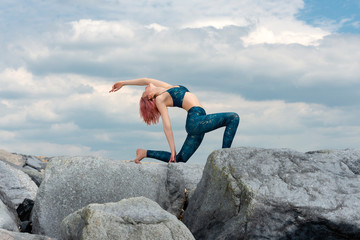 Woman practicing yoga on the rocks