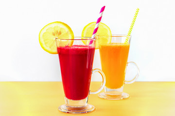 Two different colors cocktails in glass cups with straw and lemon slice. Healthy smoothies, white background.