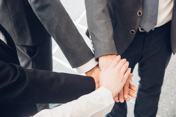 Obraz premium Colleagues Stacking Hands While Standing Against Buildings In City