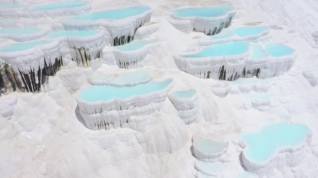 Natural travertines in Pamukkale, Turkey. Thermal springs located on white limestone terraces. Aerial footage 4k
