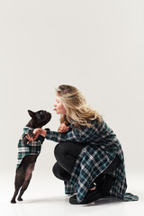 Young woman is training a dog, french bulldog puppy. Gives him yummy vitamins. The dog is standing on its hind legs.