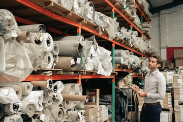 Mananger holding a clipboard while doing his warehouse inventory