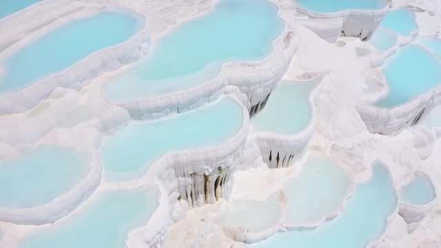Flying over the travertines in Pamukkale, Turkey. White limestone mineral formations. Aerial footage 4k