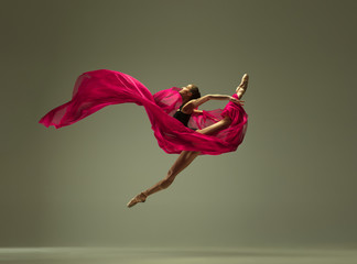 Graceful ballet dancer or classic ballerina dancing isolated on grey studio background. Woman with the pink silk cloth. The dance, grace, artist, contemporary, movement, action and motion concept.