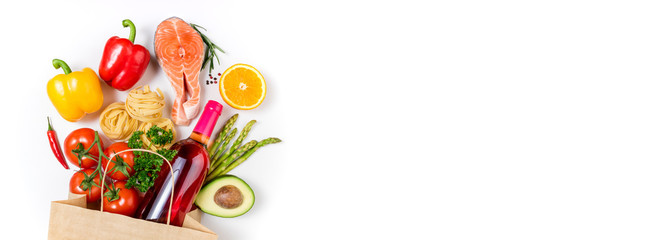 Healthy food background. Healthy food in paper bag fish, pasta, vegetables, fruits and wine on white background. Shopping food supermarket concept. Healthy eating, cooking dinner concept. Copy space