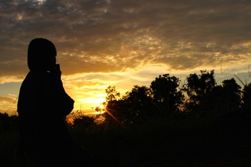  The silhouette of a girl sitting in front of him, a golden yellow sky in the evening