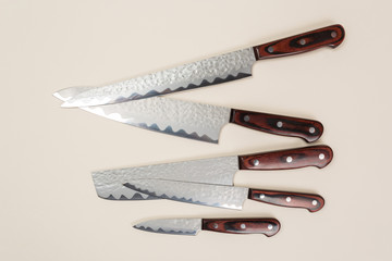 Several different used stainless steel kitchen knives with brown wooden handles