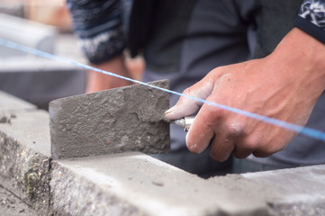 Worker puts bricks, trowel tool in hand