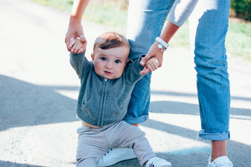 Cute baby boy with woman hands background outdoors