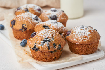 Blueberry muffin, side view, close up. Cupcakes with berries on white concrete table, breakfast with cake and milk
