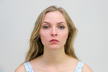 I have loose hair and beautiful eyes. I do not need to wriggle in front of the camera. Portet close up of a beautiful blonde woman on a gray background without emotion.
