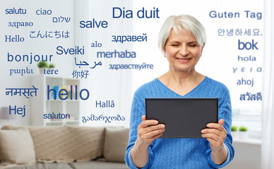 technology, online translator and old people concept - smiling senior woman using tablet computer...