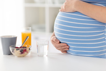 pregnancy, healthy eating and maternity concept - close up of pregnant woman touching her belly...