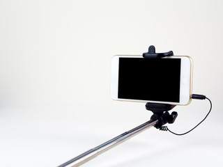 Selfie stick with mobile phone on the white background