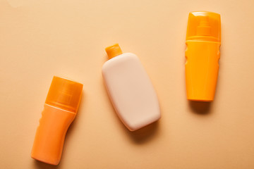 top view of sunscreen products in bottles on beige background