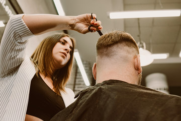 the barber cuts a bearded man with scissors in the salon