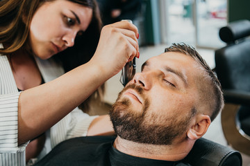 Obraz na płótnie Canvas the barber cuts his beard to a brutal man in the salon