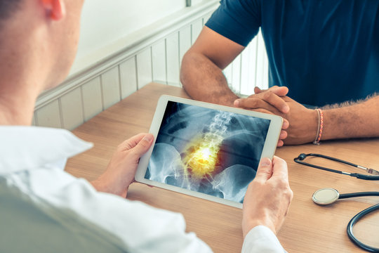 Doctor holding a digital tablet with x-ray of hips of the patient with pain on the spine