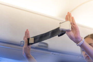 Air hostess shows how to use a presenting a seat belt fastening on board.