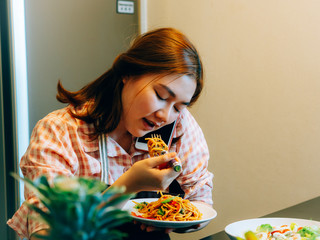 Woman talking mobile and eating the spaghetti in the kitchen