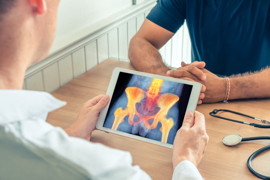 Doctor holding a digital tablet with x-ray of hips and spine of the patient