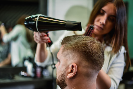 girl hairdresser dries hair to a man in a salon